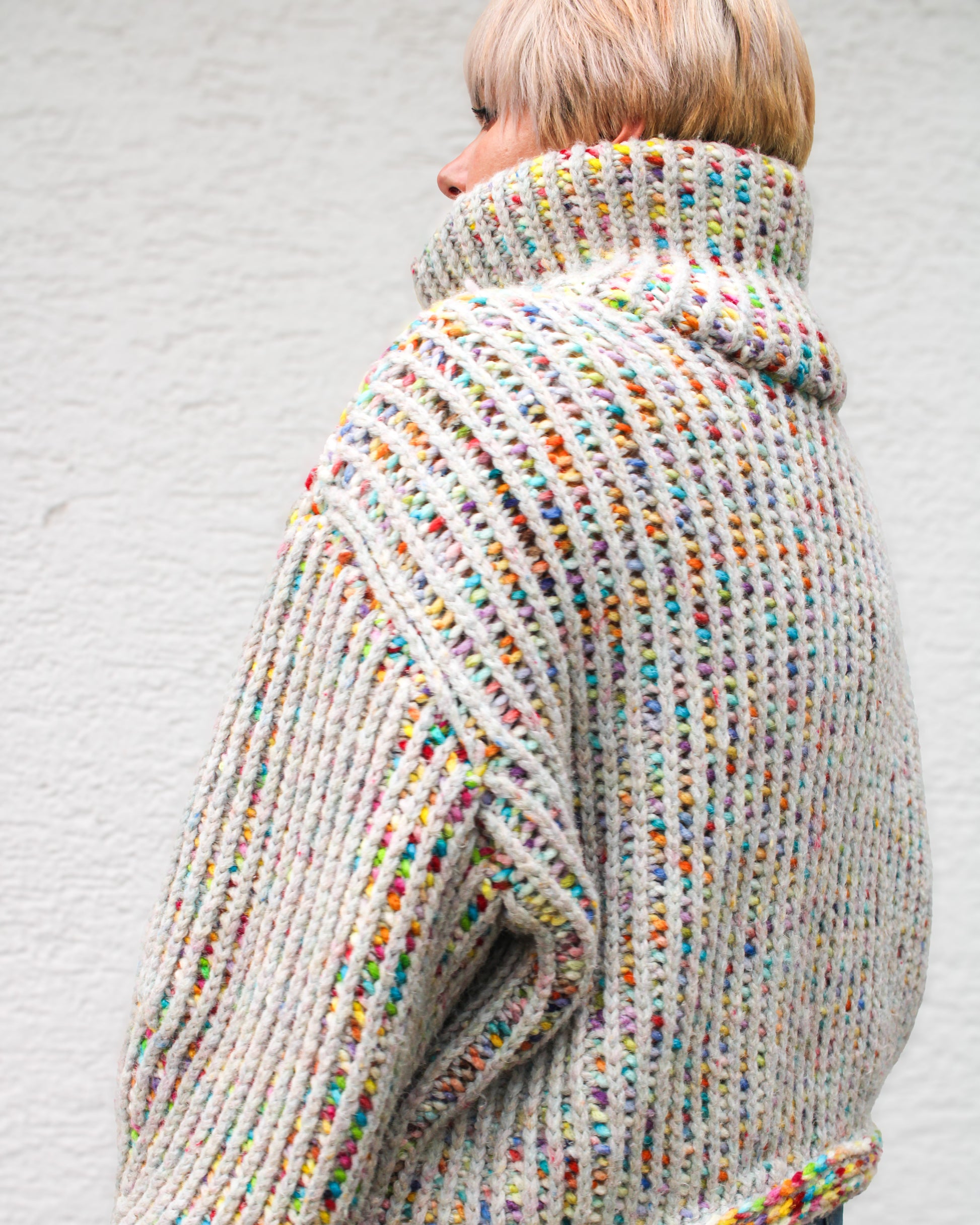 Pattern designer wearing a size MEDIUM Brioche Crochet Pullover in the Confetti colorway, back view showing the brioche column architecture in dramatic drop-shoulder detail.